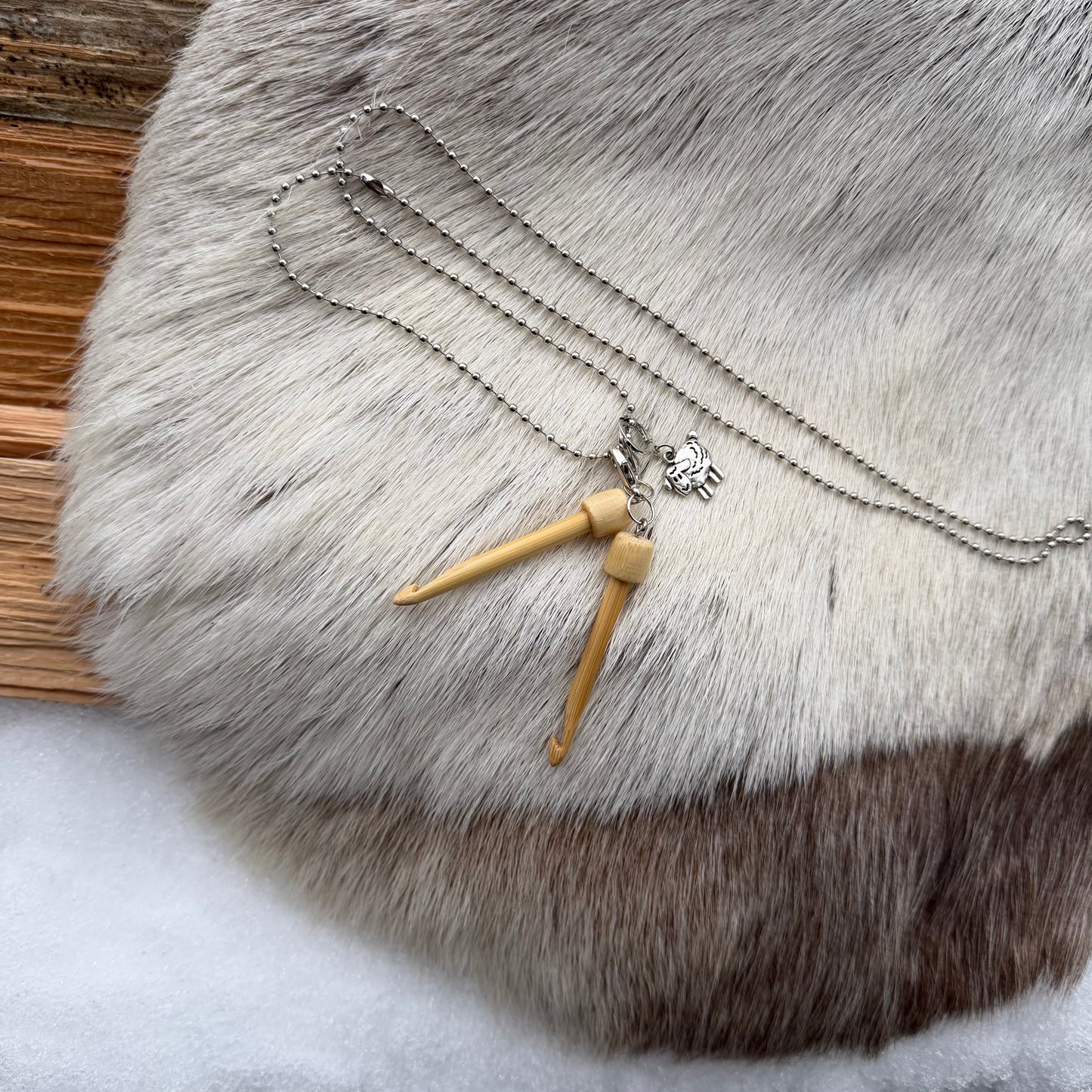 Kätevä roikkuva kaulakoru, jossa on kaksi mini-virkkuukoukkua ja suloinen lammas-merkki